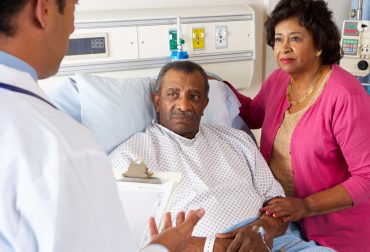 Doctor Talking To Senior Couple On Ward